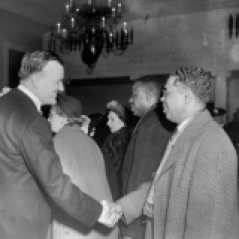 (Mayor or Governor) Theodore McKeldin shaking hands with Martin Jenkins, President of Morgan State College. Unidentified people and police officers in background. circa 1951. Paul Henderson, HEN.00.B1-067.