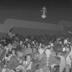 Children and adults seated inside unidentified theater, circa 1962. Paul Henderson, HEN.00.B1-005.