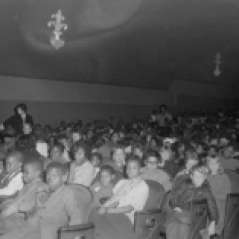 Children and adults seated inside unidentified theater, circa 1960. Paul Henderson, HEN.00.B1-024.