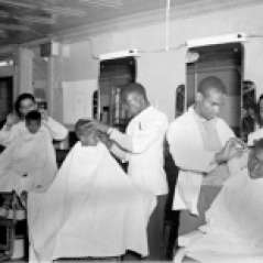 Interior of barbershop with customers and barbers, circa 1949. Paul Henderson, HEN.00.B1-104.