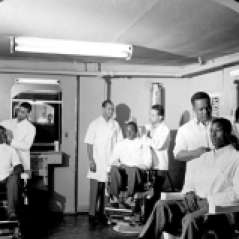Interior of barbershop with customers and barbers, circa 1949. Paul Henderson, HEN.00.B1-109.