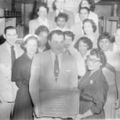 Men and women presenting plaque to Samuel L. Hendin of Hendin's Hollywood Fashions clothing store, circa 1952. Paul Henderson, HEN.00.B1-143.